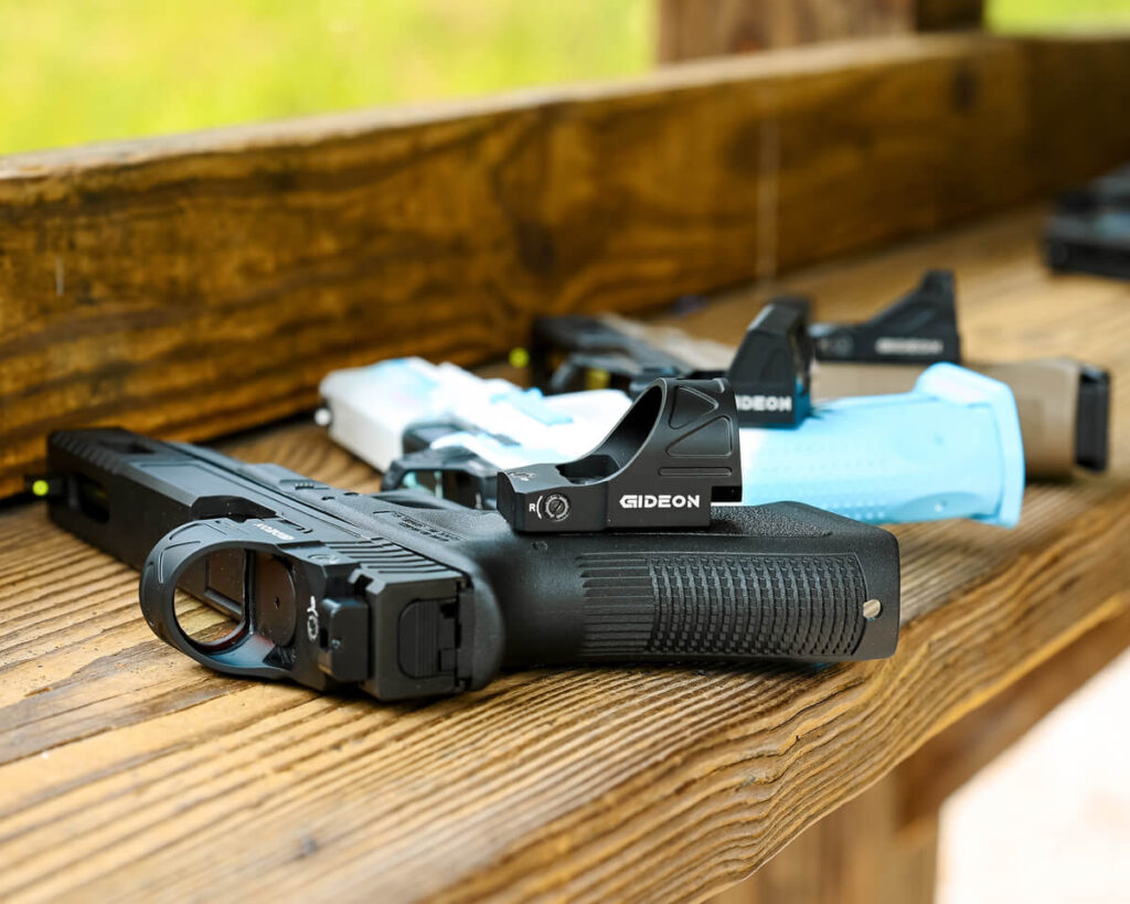 Various pistols sitting on a shelf with Gideon Optics reflex sights placed on top of them