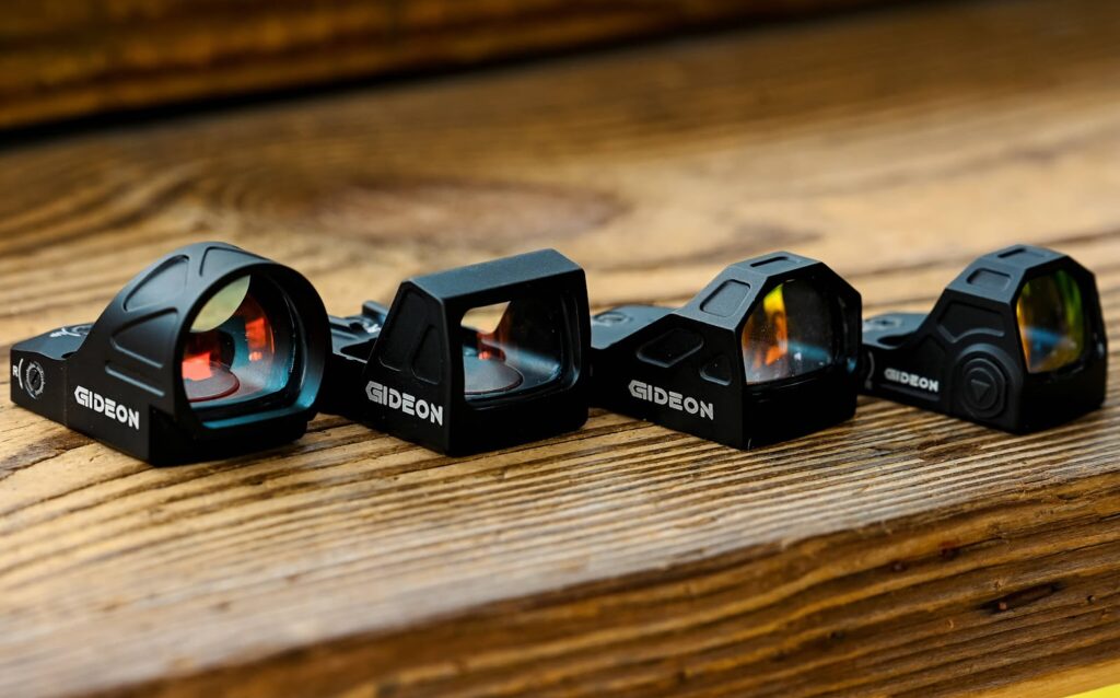 Four of Gideon Optics red dot sights placed on a wooden table