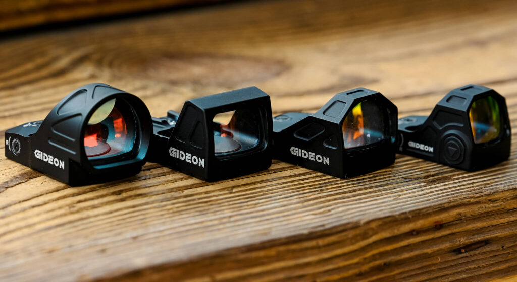 Four different Gideon Optics red dot sights placed on a wooden table