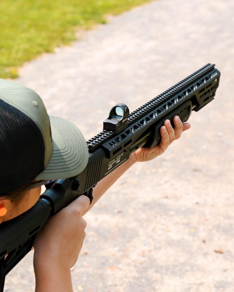 Man zeroing in a red dot sight mounted to a 12 gauge shotgun