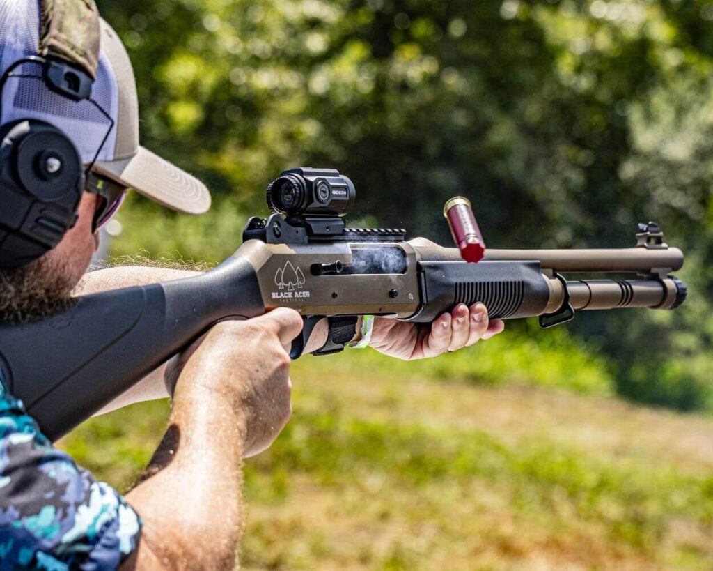 Man firing a shotgun with a Gideon optics Advocate mounted
