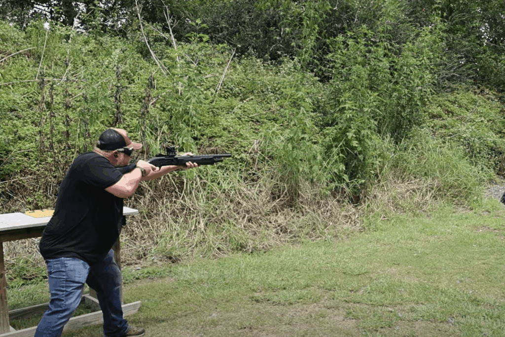 Man firing a shotgun at a target at an outdoor shooting range - Gideon Optics Man firing a shotgun at a target at an outdoor shooting range