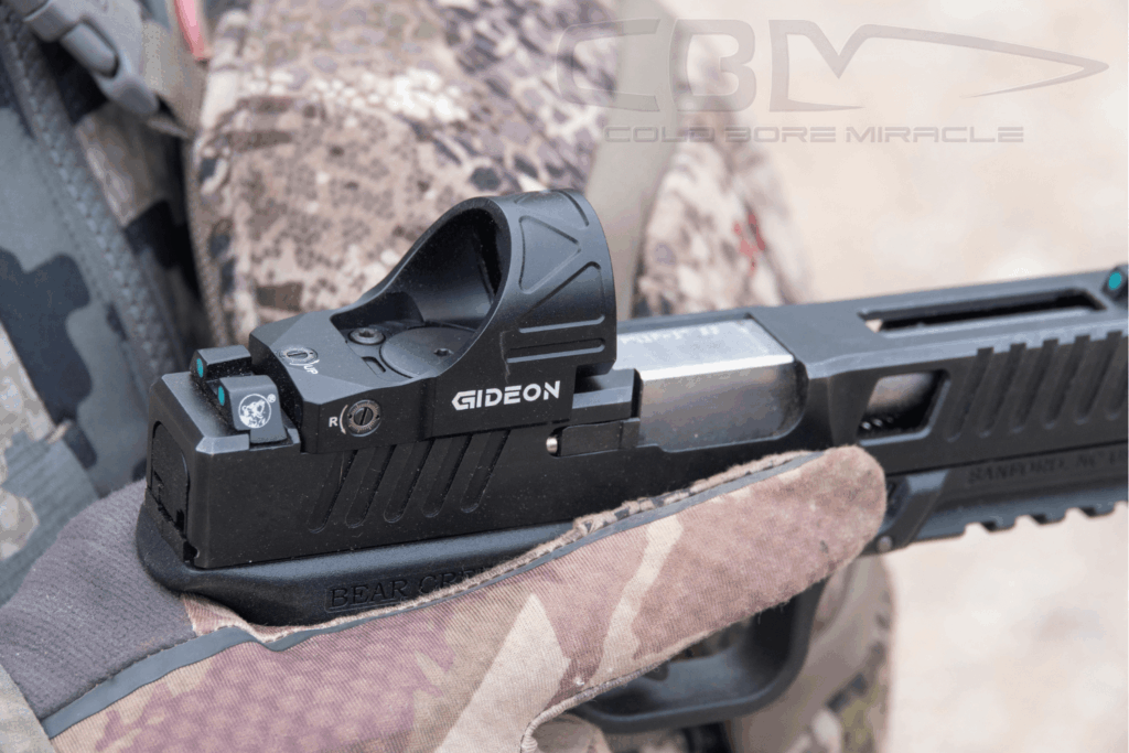 Close up of a gloved hand holding a pistol with a Gideon Optics red dot mounted