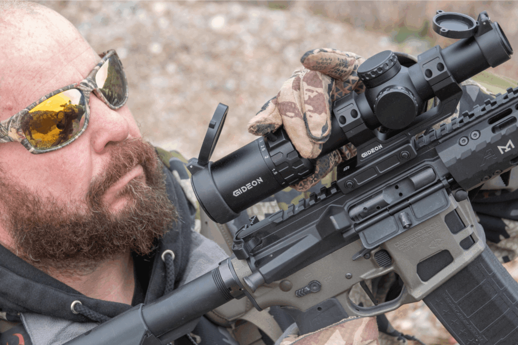 Man wearing winter gear holding a firearm with a Gideon Optics scope mounted