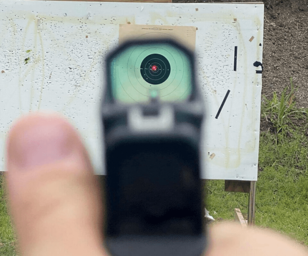 view through optic of red dot reticle at an outdoor range