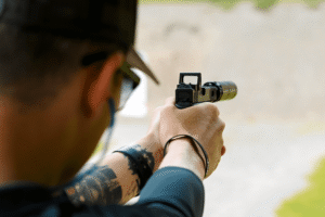 Man aiming a pistol at a target. The pistol has a Gideon optics red dot mounted