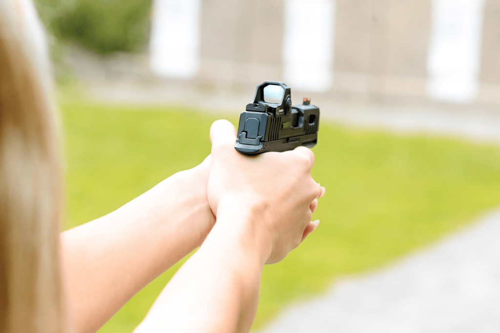 Woman holding and aiming a pistol with a Gideon Optics red dot mounted